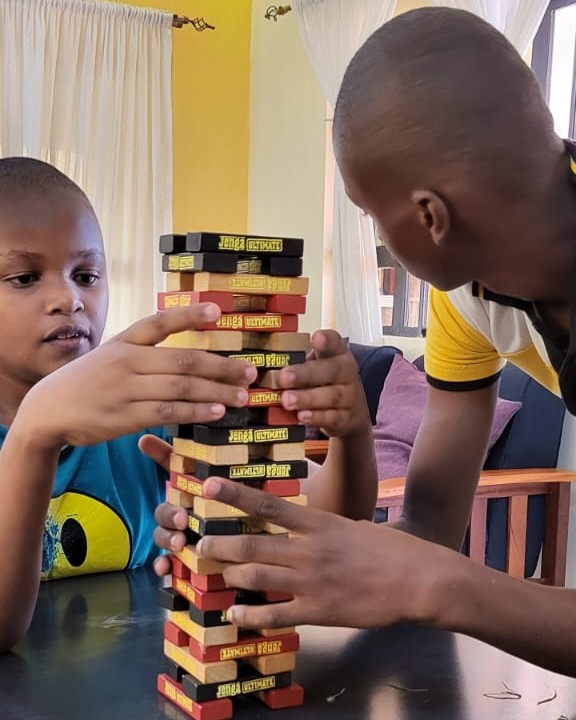 A learner and a member of staff building a tower of wooden blocks together at a table